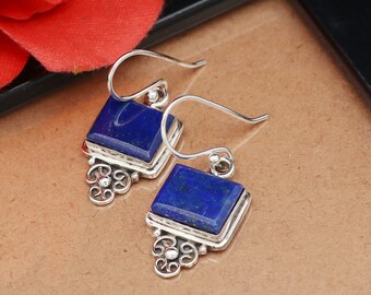 May include: A pair of silver earrings with square blue lapis lazuli stones. The earrings have a delicate, ornate design.