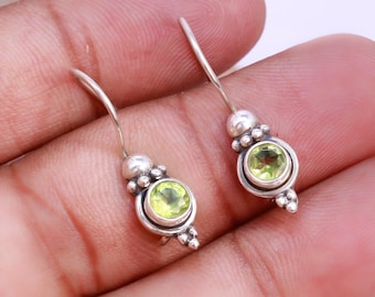 May include: A pair of silver earrings with green gemstone accents. The earrings have a simple, elegant design and are perfect for everyday wear.