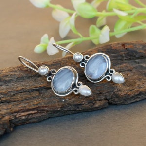 Puede incluir: Pendientes de plata con una piedra de ágata gris y detalles de perlas blancas.