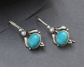 May include: A pair of silver dangle earrings with turquoise stones and small pearl accents.