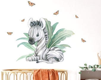 May include: A watercolor illustration of a baby zebra sitting in a patch of green leaves with orange butterflies flying around it. The illustration is on a white background.
