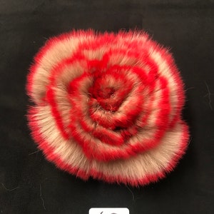 May include: A red and white fur rose with a white tag that says "63" on a black background.