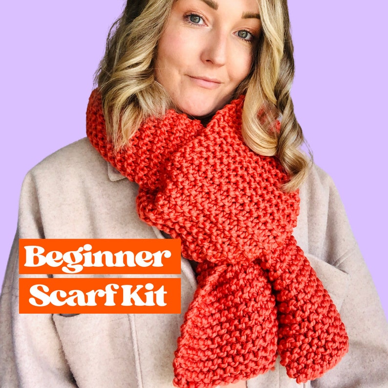 May include: A beginner scarf kit featuring a red knitted scarf. The scarf is made with a chunky yarn and has a simple stitch pattern. The kit includes everything you need to make your own scarf, including yarn, needles, and instructions.