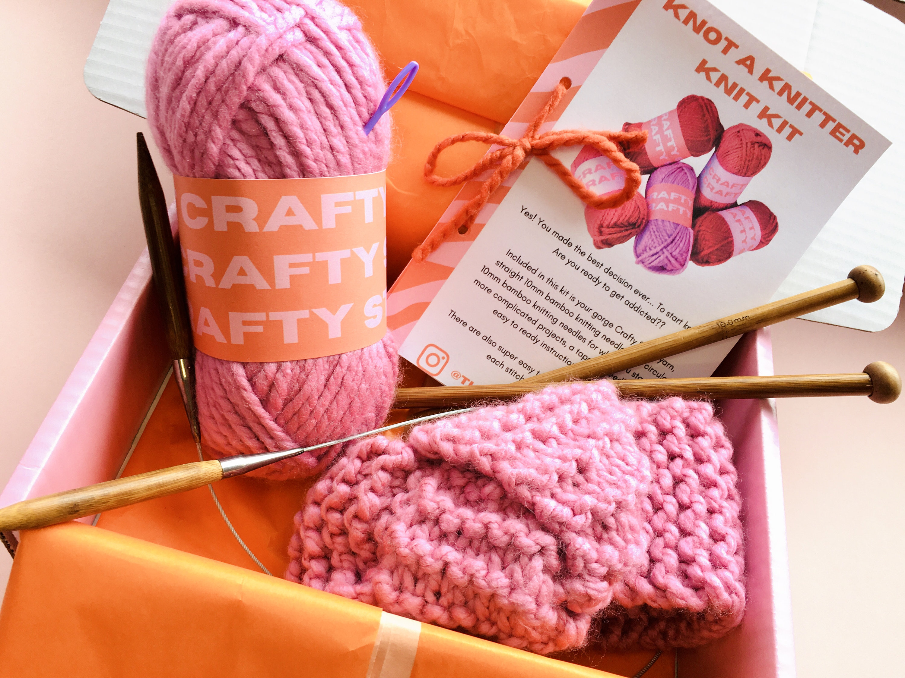 May include: A pink knitting kit with bamboo knitting needles, pink yarn, and a partially knitted pink hat. The kit includes instructions for knitting projects. The packaging has the text "Knot a Knitter Knit Kit" and "Crafty Raffy Aftys".