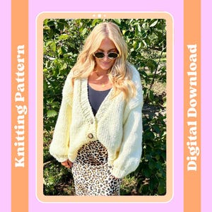 May include: A light yellow knitted cardigan with a button closure. The cardigan has a V-neck and long sleeves. The model is wearing the cardigan with a black tank top and a leopard print skirt. The image is set against a backdrop of green foliage.