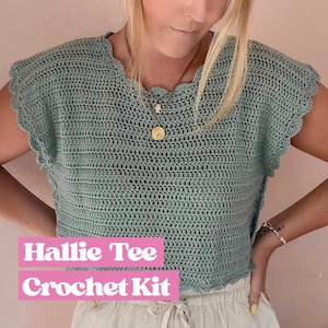Peut inclure: Un haut en crochet vert clair avec un col et des manches festonnés. Le texte "Hallie Tee Crochet Kit" est affiché dans un encadré rose. Le haut est fait d'une matière tissée lâche. Le haut fait partie d'un kit de crochet.
