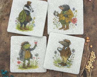 May include: Set of four square coasters featuring whimsical illustrations of anthropomorphic animals. Each coaster depicts a different character: a badger, a mole, a frog, and a rat, all dressed in vintage attire and set against a floral background.