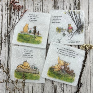 May include: Set of four Winnie the Pooh-themed coasters with quotes from the book. Each coaster features a different scene with Winnie the Pooh and his friends. The quotes are: "How lucky am I to have something that makes saying goodbye so hard." "If you live to be a hundred, I want to live to be a hundred minus one day... so I never have to live without you." "We didn't know we were making memories. We just knew that we were having fun." "I think we dream so we don't have to be apart for so long. If we're in each other's dreams, we can be together all the time."