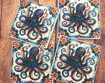 May include: Four square ceramic coasters with a white background and blue and gold octopus illustrations. The octopus has eight tentacles and is surrounded by a floral pattern.