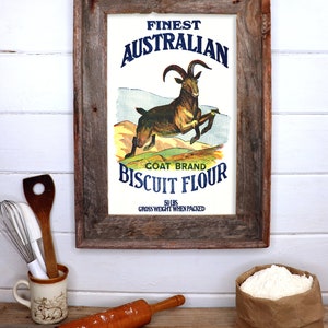 K&ouml;nnte beinhalten: Ein Vintage-Rahmenbild einer Werbeanzeige f&uuml;r Goat Brand Biscuit Flour. Das Bild zeigt eine springende Ziege mit einem blauen und wei&szlig;en Text&uuml;berlagerung, der "Finest Australian Goat Brand Biscuit Flour 50 lbs Gross Weight When Packed" lautet.