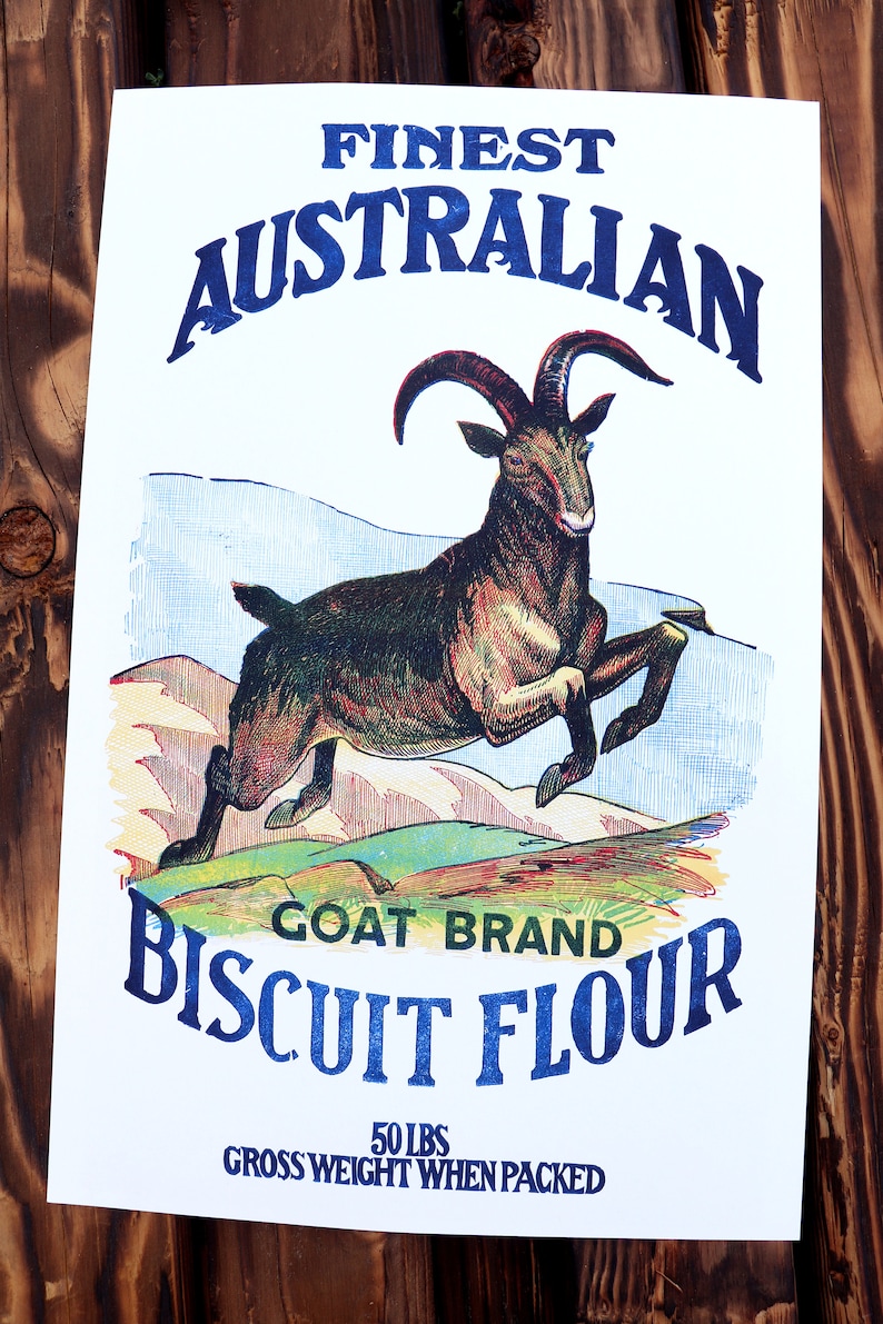 K&ouml;nnte beinhalten: Vintage-Illustration eines springenden Ziegenbocks vor einer Bergkette. Der Text lautet "Finest Australian Goat Brand Biscuit Flour 50 lbs Gross Weight When Packed".