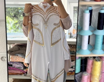 May include: White leotard with gold and silver accents. The leotard has a high neckline and long sleeves. It features a geometric design with a diamond pattern.
