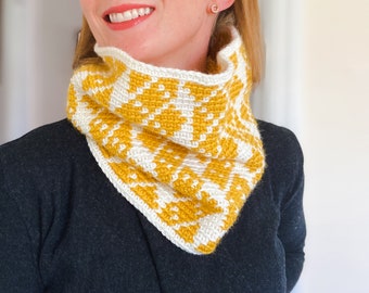 May include: A yellow and white crocheted cowl with a geometric pattern. The cowl is worn by a person with a black shirt.