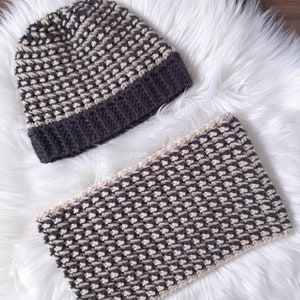 Puede incluir: Un gorro y una bufanda a juego de punto gris y beige. El gorro tiene un borde doblado y la bufanda es un rect&aacute;ngulo largo.