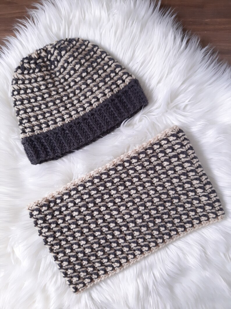 Puede incluir: Un gorro y una bufanda a juego de punto gris y beige. El gorro tiene un borde doblado y la bufanda es un rect&aacute;ngulo largo.