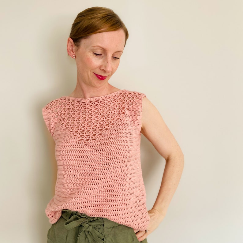 May include: A pink crochet top with a delicate openwork design around the neckline and sleeveless.