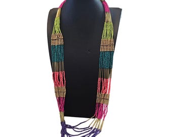 May include: A multi-strand necklace with a variety of colorful beads. The necklace features sections of green, teal, pink, and purple beads, interspersed with gold-colored metal bars and beads. The necklace is displayed on a black mannequin.