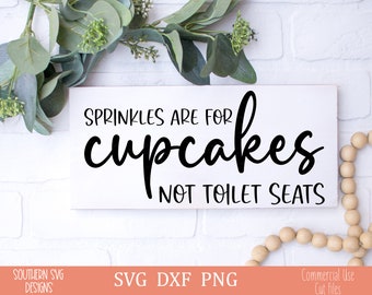 May include: White wooden sign with black text that reads "Sprinkles are for cupcakes not toilet seats".