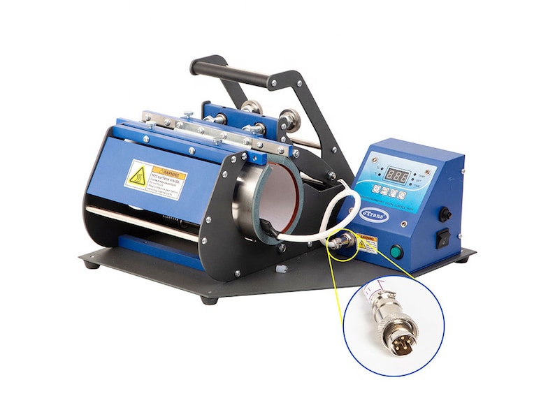 May include: A blue and black mug press machine with a digital display and handle. The machine has a cylindrical heating element and a control panel with buttons and a digital display. A white cable connects to the machine.
