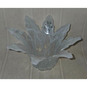 May include: A white glass decorative bowl with a flower-like design. The bowl has a wide, open shape with petal-like edges and a textured, marbled appearance. A small sticker is visible on the side.