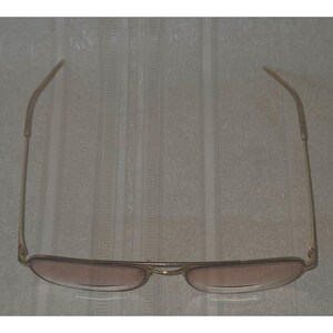 Puede incluir: Gafas de sol de aviador doradas con lentes tintadas en marr&oacute;n. Las gafas tienen un doble puente y varillas delgadas. Las lentes son de forma ovalada y la montura es de color dorado brillante. Las gafas se muestran sobre un fondo neutro.