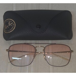 Puede incluir: Gafas de sol con montura dorada y lentes rosas degradadas y estuche de cuero negro. El logotipo de Ray-Ban es visible en el estuche. Las gafas tienen doble puente y un estilo aviador cl&aacute;sico.