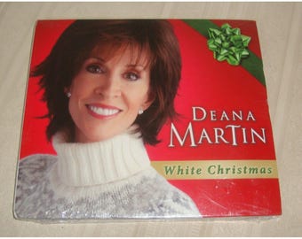 May include: A red CD case with a white Christmas theme. The front features a photo of Deana Martin, a woman with brown hair, wearing a white sweater. The text on the case reads "Deana Martin White Christmas".