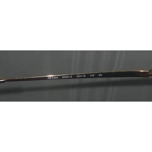 Puede incluir: Primer plano de la patilla de unas gafas. La patilla es de color dorado y tiene el texto "RB 3588 9055/13 55o19 140 3N" impreso.