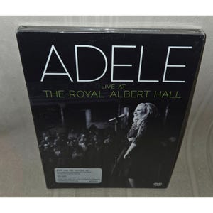 May include: A DVD and CD set of Adele's "Live at The Royal Albert Hall" concert. The cover is black with white text, featuring the artist's name and concert title. A black and white image of Adele performing is visible.