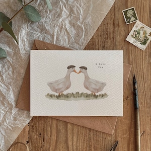 Coppia in campagna, lui e il suo simpatico disegno di anatre d'amore, biglietto di auguri ecologico