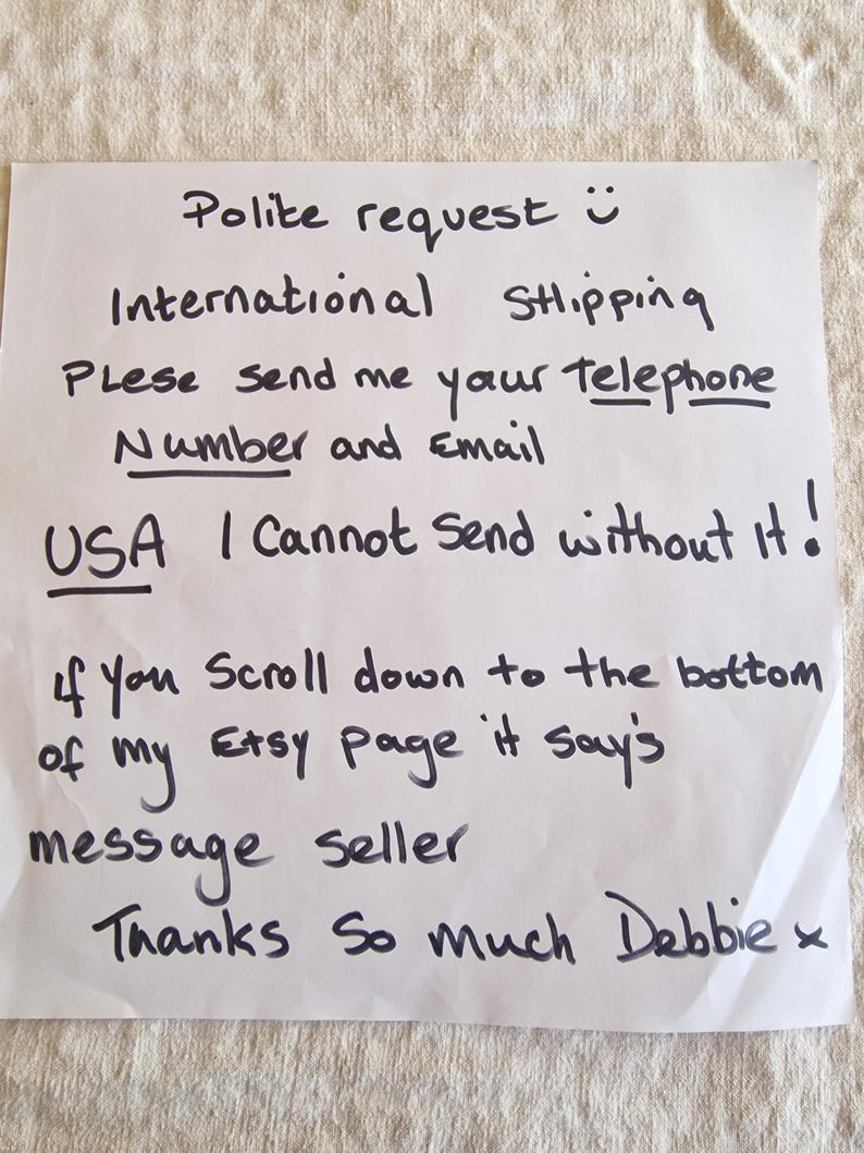 May include: A handwritten note on white paper with black ink. The text requests a phone number and email for international shipping, and mentions Etsy. The note is signed "Debbie".
