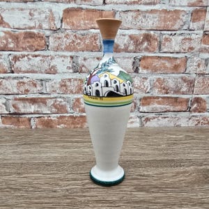 May include: A white ceramic mug with a black handle and the text "But First, Coffee" in a handwritten style. The mug is on a white surface. The mug is approximately 4 inches tall.