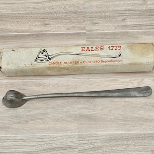 May include: A silver candle snuffer with a long handle. The snuffer is a reproduction of a circa 1740 candle snuffer. The box it comes in says "Eales 1779" and "Candle Snuffer - Circa 1740 Reproduction".