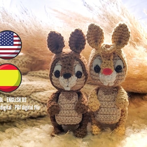 Puede incluir: Dos animales de peluche tejidos a crochet, uno marrón y otro beige, con ojos grandes y una expresión sonriente. Los animales están sentados sobre una superficie de punto beige. El texto "ESPAÑOL - ENGLISH US" y "Archivo digital - PDF digital file" es visible en la parte inferior de la imagen.
