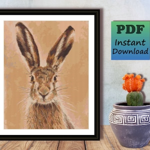 May include: A close-up of a brown rabbit with long ears looking directly at the camera. The rabbit is against a light brown background.