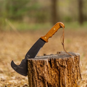 May include: A black and brown hunting knife with a leather strap is resting on a weathered tree stump in a forest setting.