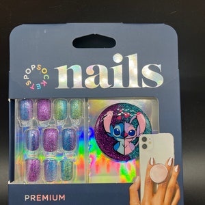 May include: A package of 30 ready-to-wear press-on nails with a glitter finish. The nails feature a blue, purple, and green color scheme. The package also includes a PopGrip phone accessory with a blue and pink Stitch character from Disney's Lilo & Stitch.