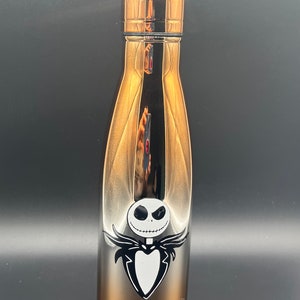 Op de afbeelding: Een roestvrijstalen waterfles met een verloop van zilver naar koper. De fles heeft een zwart-witte afbeelding van Jack Skellington uit de film "The Nightmare Before Christmas."