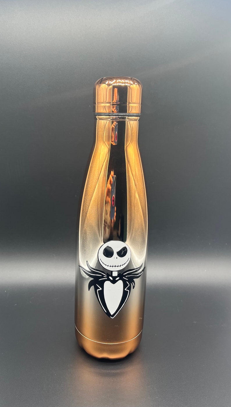Op de afbeelding: Een roestvrijstalen waterfles met een verloop van zilver naar koper. De fles heeft een zwart-witte afbeelding van Jack Skellington uit de film "The Nightmare Before Christmas."