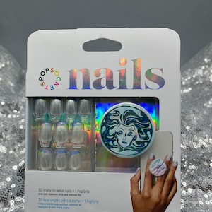 May include: A package of 30 ready-to-wear press-on nails with a holographic design. The package includes a PopGrip, prep pad, manicure stick, and mini nail file. The nails are clear with a subtle shimmer. The PopGrip features a holographic design of a woman's face with a blue and green color scheme.