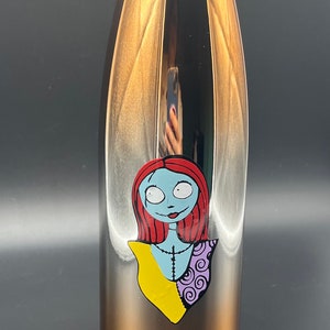 Op de afbeelding: Een koperkleurige waterfles van roestvrij staal met een afbeelding van Sally uit The Nightmare Before Christmas. De afbeelding is in zwart, wit, rood, geel en paars.