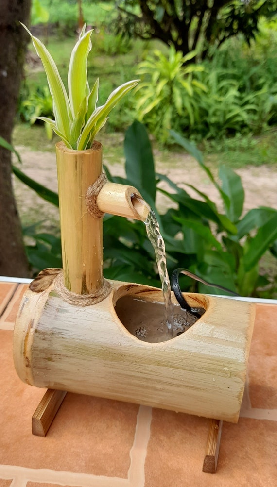 Closeup to little fountain from bamboo stick inside green vintage
