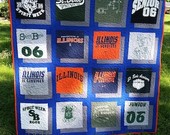 May include: A handmade quilt featuring squares of t-shirts with various logos and text. The quilt has a blue background with orange trim. Some shirts say "St. Bede Spirit Week", "Illinois", and "Senior 06".