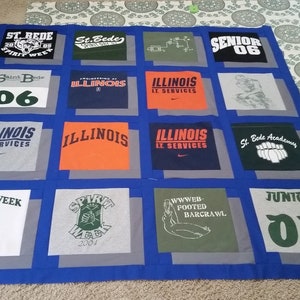 May include: A handmade quilt featuring squares of various t-shirts. The shirts display text and graphics, including "ILLINOIS," "SPIRIT WEEK," and "SENIOR 06." The quilt has a blue border and gray squares, showcasing a unique, personalized design.