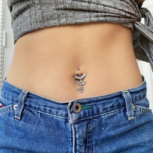 May include: A silver belly button ring with a dangling charm of three bats.