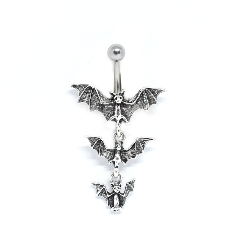 May include: Silver belly button ring with three dangling bats. The bats are in a descending size order, with the largest bat at the top and the smallest bat at the bottom.