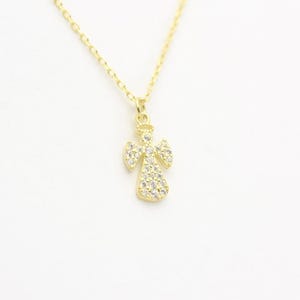 May include: A gold-colored angel pendant necklace. The angel pendant is adorned with small, clear gemstones. The necklace has a delicate chain and is set against a white background. The jewelry is suitable for everyday wear.