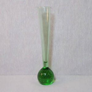 May include: A tall, clear glass vase with a green, bubbled base. The vase is slender and has a rounded, bulbous base.