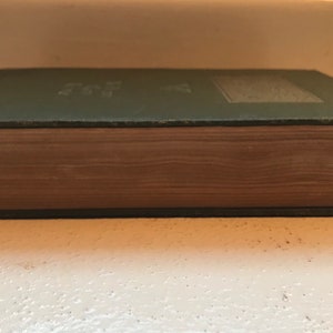 May include: A green hardcover book with a brown spine. The book is closed and the spine is visible.
