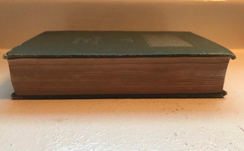May include: A green hardcover book with a brown spine. The book is closed and the spine is visible.